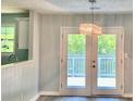 Bright dining area featuring a stylish light fixture and patio doors leading to an outdoor deck and green scenery at 6906 Shangrila Way, Riverdale, GA 30296