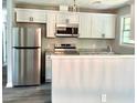 Modern kitchen featuring stainless steel appliances, white cabinets, granite countertops, and stylish backsplash at 6906 Shangrila Way, Riverdale, GA 30296