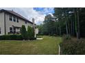 Landscaped backyard featuring a spacious lawn, patio area, and mature trees at 2819 Heritage Oaks Cir, Dacula, GA 30019
