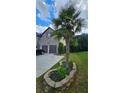 Home with an attached two-car garage, a circular stone bordered garden, and mature palm tree at 2819 Heritage Oaks Cir, Dacula, GA 30019