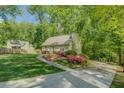 The front of this charming home shows a curved sidewalk and a driveway leading to the house with mature landscaping at 3957 Woodland Cir, Conyers, GA 30013
