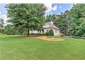 Expansive front yard with mature trees, garden beds, and lush lawn offering privacy at 4825 Whispering Pine Way, Cumming, GA 30028