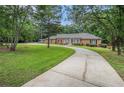 Wide shot of the home's exterior, long driveway, and manicured lawn surrounded by mature trees at 3003 Hanover Se Ln, Conyers, GA 30094