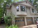 Three-car garage with tan doors, multiple windows and stone accents at 390 Hunt River Way, Suwanee, GA 30024