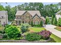 Gorgeous exterior view of a stone and brick home with well-manicured lawn and mature trees at 6470 Long Island Nw Dr, Atlanta, GA 30328