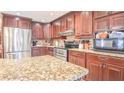 A modern kitchen boasts stainless steel appliances, rich wood cabinets, and granite countertops at 5028 Jamie Ne Ct, Woodstock, GA 30188