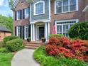 Inviting front entrance with brick steps, an American flag, and lush, colorful landscaping at 658 Vinings Estates Se Dr, Mableton, GA 30126