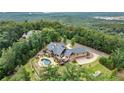 Aerial view of a beautiful home with a private pool and lush landscaping overlooking trees and a lake at 49 Waterside Se Dr, Cartersville, GA 30121