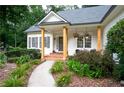 Inviting covered front porch with wood columns, a brick walkway, and charming floral accents for a welcoming entrance at 6490 Ivey Hill Dr, Cumming, GA 30040