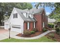 A two-story brick home with a three-car garage, manicured lawn and sidewalk at 1418 Mill Path Loop, Lawrenceville, GA 30045