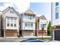 View of townhome with a stone facade, second story balcony, and attached garage at a neighborhood intersection at 164 Blakemore Dr, Smyrna, GA 30080