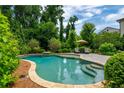 Stunning backyard pool featuring lush landscaping, stone pavers and two lounge chairs under an umbrella at 1282 Kendrick Ne Rd, Brookhaven, GA 30319