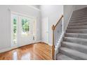 Bright foyer with hardwood floors, stairs with a carpet runner, and a glass-paneled front door at 9996 Village South Dr, Douglasville, GA 30135