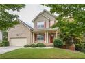 Charming two-story home featuring a brick facade, red shutters, a manicured lawn, and an attached two-car garage at 3439 Tupelo Trail, Auburn, GA 30011