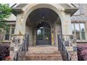 Stone and brick front entrance with arched doorway and black metal railing at 2452 Stone Manor Ne Dr, Buford, GA 30519