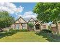 Inviting brick home featuring an arched entryway, manicured lawn, and lush landscaping in a desirable neighborhood at 2452 Stone Manor Ne Dr, Buford, GA 30519