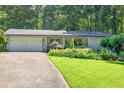 Charming home featuring a well-manicured lawn and inviting curb appeal with mature trees and landscaping at 6077 Lake Lanier Heights Rd, Buford, GA 30518