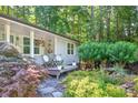 Quaint front porch with a cozy seating area, surrounded by lush landscaping and a serene garden at 6077 Lake Lanier Heights Rd, Buford, GA 30518