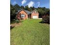 Charming single-story brick home featuring an attached two-car garage and a well-maintained lawn with lovely flower bushes at 709 Stonehenge Pl, Jonesboro, GA 30236