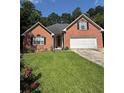 Charming single-story brick home featuring an attached two-car garage and a well-maintained lawn with lovely flower bushes at 709 Stonehenge Pl, Jonesboro, GA 30236