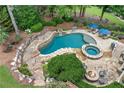 Resort-style pool with a spa, stone waterfall, surrounding rock features, and outdoor seating area at 7025 Windsor Hill Psge, Suwanee, GA 30024