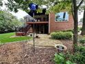 This backyard features a deck with stairs, a stone patio, lush landscaping, and mature trees at 810 Doe Hill Ln, Roswell, GA 30075