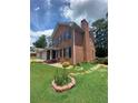 Exterior view of brick home with front lawn, landscaping, and mature trees at 1165 Vineyard Ct, Stone Mountain, GA 30083
