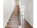 Bright, carpeted staircase with white walls, wooden banister and hardwood flooring at 5843 Taka Ln, Lithonia, GA 30038
