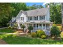 Traditional home with a covered porch, white lattice, and lush greenery in a serene setting at 440 Junction Trak, Roswell, GA 30075