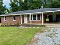 Inviting brick home featuring a covered carport, new landscaping and a freshly painted front door at 882 Campbell Rd, Covington, GA 30014