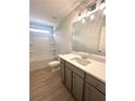Bathroom with vanity, gray cabinets, quartz countertop, wood-look floor, and tub at 3065 Zodiac Ct, Lawrenceville, GA 30044