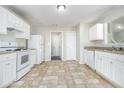 Well-lit kitchen featuring white cabinets, appliances, and neutral countertops at 6595 Browns Mill Ferry Dr, Lithonia, GA 30038