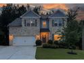 Charming two-story brick home with a well-manicured lawn and a two-car garage at dusk at 302 Aspen Valley Ln, Dallas, GA 30157