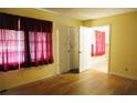 Bedroom with wood flooring, and large window with sheer red curtains at 127 Perry St, Loganville, GA 30052