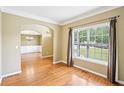 View of the formal living room featuring hardwood floors, crown molding, and natural light from a large window at 2359 Saint Kennedy Ln, Buford, GA 30518
