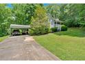 View of home and carport with long drive and green lawn surrounded by large trees at 144 Wiley Dr, Douglasville, GA 30134