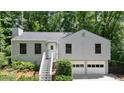 Charming home with manicured lawn, inviting entryway stairs, and two-car garage nestled among mature trees at 7025 Stone Wood Nw Dr, Kennesaw, GA 30152