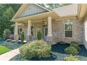 Close up of landscaped front yard and covered porch with columns on a single-story brick home at 150 Whitworth Dr, Locust Grove, GA 30248