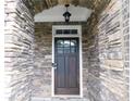 Stone archway highlights the dark wooden front door with glass panes, creating an inviting entrance at 330 La Perla Dr, Sugar Hill, GA 30518