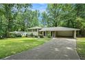 Split-level home with well-maintained lawn, brick facade, and covered parking, surrounded by mature trees at 1534 Sw Austin Sw Rd, Atlanta, GA 30331