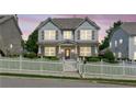 Charming two-story home at dusk featuring a white picket fence, landscaped yard, and inviting front porch at 3725 Downing Dr, Cumming, GA 30040