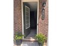 Inviting brick home entrance with a welcoming open door, black door hardware and ferns at 531 Headwind Way, Alpharetta, GA 30005