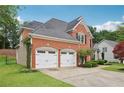 Exterior view of a brick house with a manicured lawn and a three-car garage, showcasing its architectural design at 2009 Mclain Nw Rd, Acworth, GA 30101
