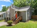 Home featuring neutral siding, a vibrant orange front door, inviting steps, and a neatly landscaped yard at 4679 Candlewyck Way, Buford, GA 30518
