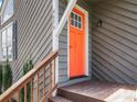 Close up of a bright orange front door, complemented by neutral siding and wood railing steps at 4679 Candlewyck Way, Buford, GA 30518