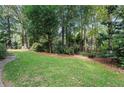 A leafy backyard featuring lush lawn, mature trees, and stepping stone pathway at 3609 Meadow Chase Dr, Marietta, GA 30062