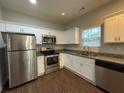 Modern kitchen with stainless steel appliances, white cabinets, granite countertops, and wood-look flooring at 241 Coral Cir, Mcdonough, GA 30253