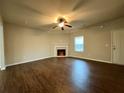 Bright living room boasts wood floors, a ceiling fan, a fireplace, and natural light streaming through a window at 241 Coral Cir, Mcdonough, GA 30253