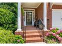 Inviting brick front porch with elegant columns and black metal railings, framed by lush hydrangea bushes at 3401 Village Green Dr, Roswell, GA 30075