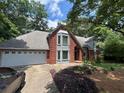 Elegant brick home with a two-car garage, arched entryway, and beautiful landscaping enhancing curb appeal at 4819 Coppedge Trl, Peachtree Corners, GA 30096